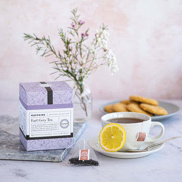 Box of Earl Grey Pyramid Tea Bags alongside a cupe and saucer with slice of lemon