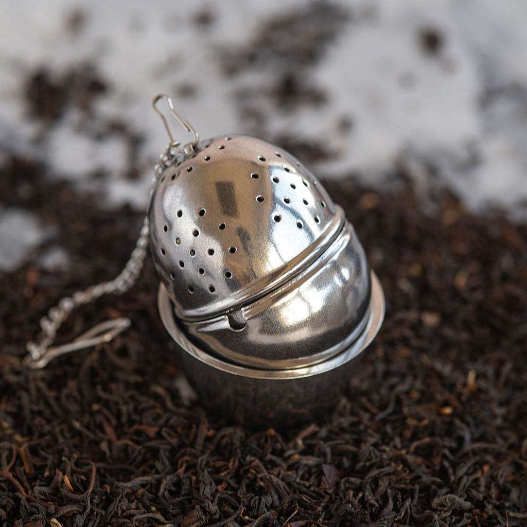 Stainless Steel tea Strainer with Drip Cup on a bed of tea leaves